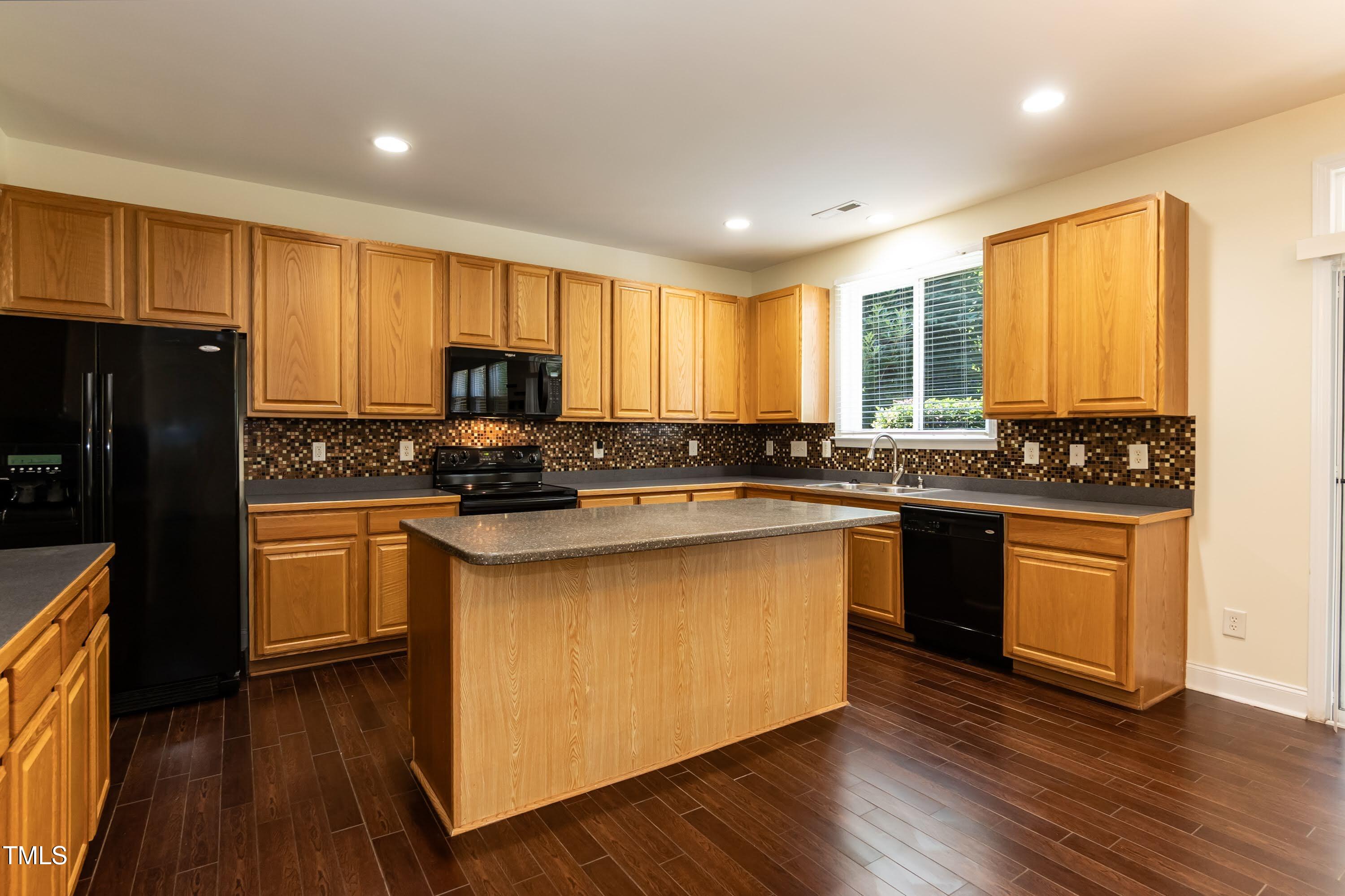 418 Byrams Ford Drive Cary, NC 27513 - Photo 17 of 53 a kitchen with granite countertop wooden floors stainless steel appliances a sink and a window