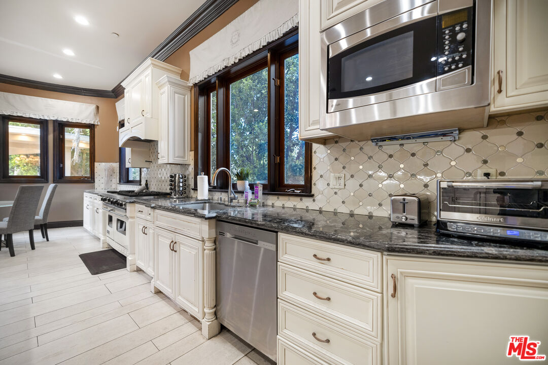 18607 Cassandra Street Tarzana, CA 91356 - Photo 21 of 58 a kitchen with stainless steel appliances granite countertop a stove a sink and a microwave