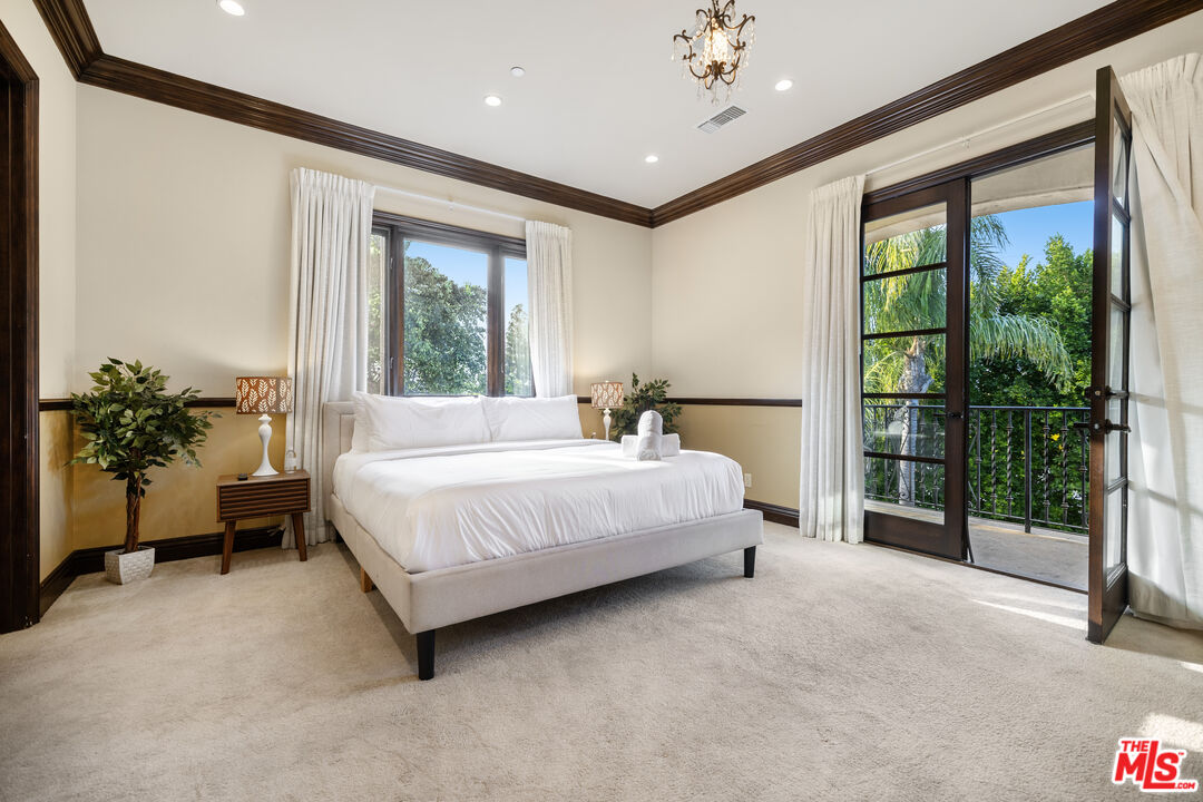 18607 Cassandra Street Tarzana, CA 91356 - Photo 32 of 58 a spacious bedroom with a large bed and a chandelier