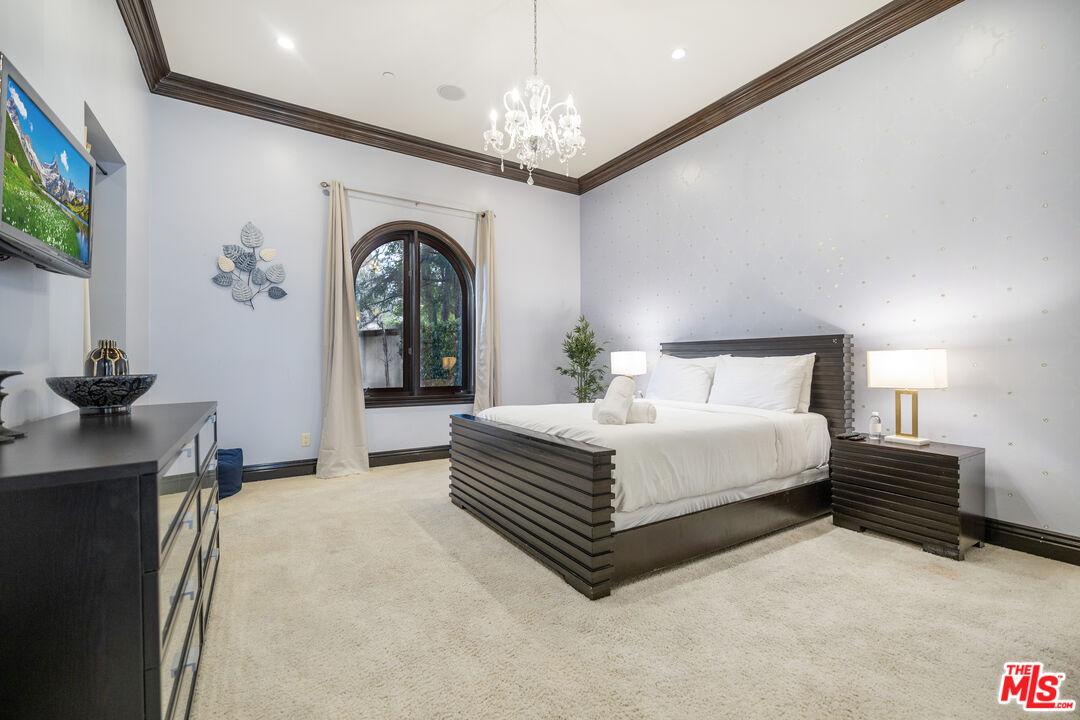 18607 Cassandra Street Tarzana, CA 91356 - Photo 43 of 58 a spacious bedroom with a bed and a chandelier