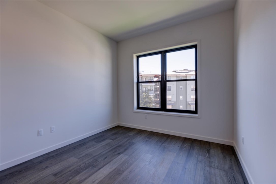 800 Embassy Drive, Unit 233 Austin, TX 78702 - Photo 18 of 40 an empty room with wooden floor and windows