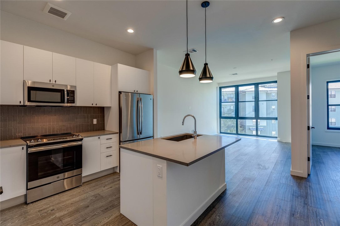 800 Embassy Drive, Unit 233 Austin, TX 78702 - Photo 6 of 40 a kitchen with stainless steel appliances granite countertop a kitchen island hardwood floor sink and stove