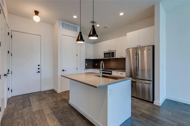 a kitchen with stainless steel appliances granite countertop a sink refrigerator and microwave