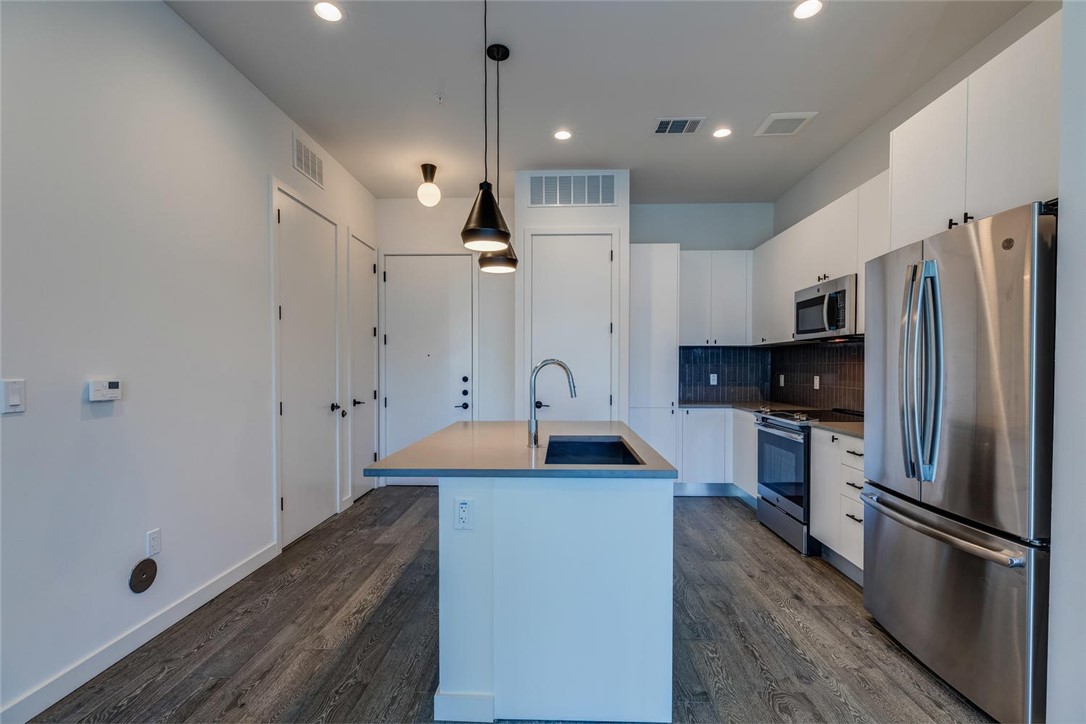 800 Embassy Drive, Unit 233 Austin, TX 78702 - Photo 8 of 40 a kitchen with stainless steel appliances granite countertop a sink refrigerator and microwave