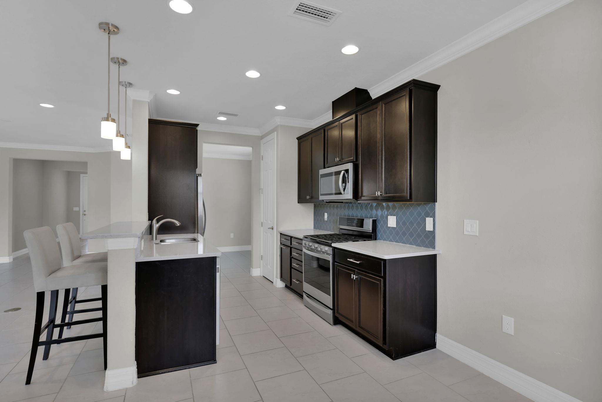 164 Front Door Lane St. Augustine, FL 32095 - Photo 11 of 42 a kitchen with kitchen island stainless steel appliances a sink stove and cabinets