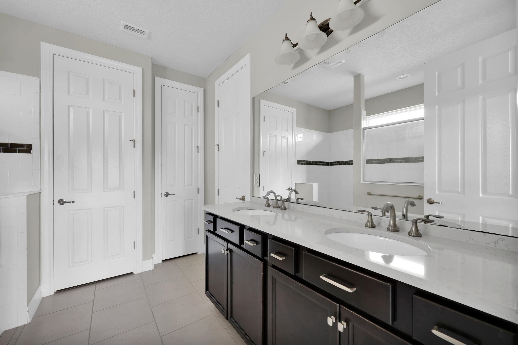 164 Front Door Lane St. Augustine, FL 32095 - Photo 23 of 42 a bathroom with a double vanity sink a mirror and a shower