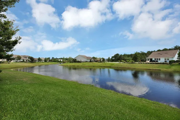 a view of an empty room with wooden floor and a bathroom
