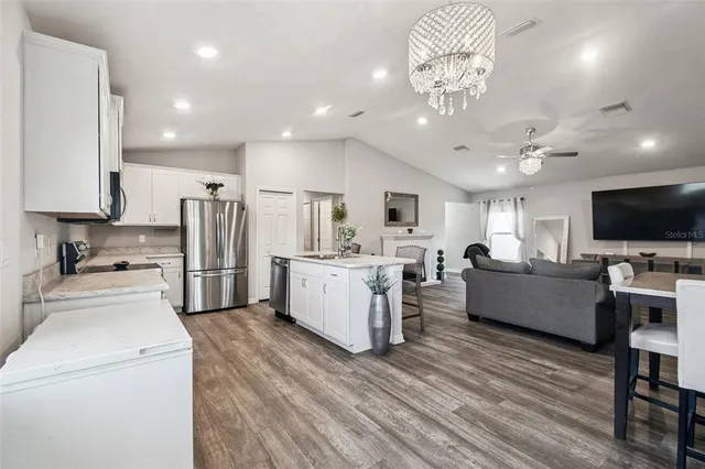 a kitchen with granite countertop a refrigerator stove top oven and sink