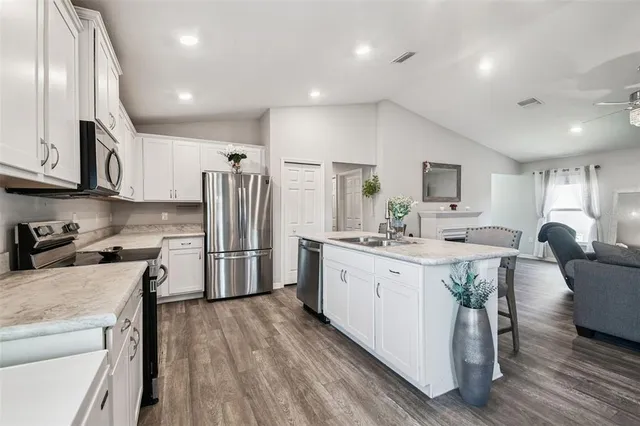 a kitchen with kitchen island a dining table chairs and refrigerator