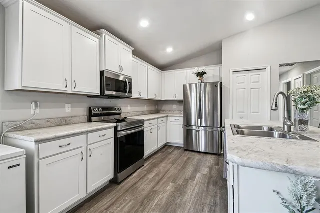 a kitchen with stainless steel appliances a dining table chairs refrigerator and sink