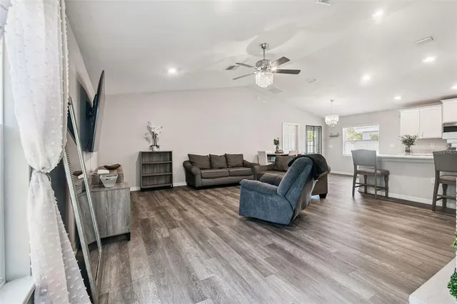 a living room with furniture a flat screen tv and a wooden floor