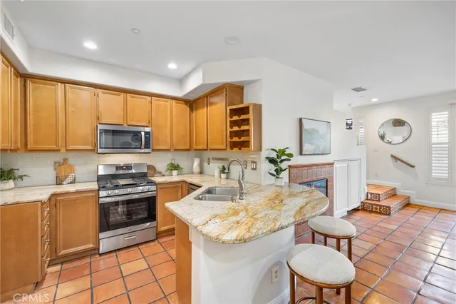 a kitchen with granite countertop kitchen island stainless steel appliances a stove a sink a microwave a refrigerator and cabinets