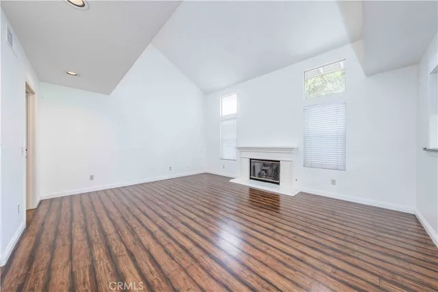 a view of empty room with wooden floor and fireplace