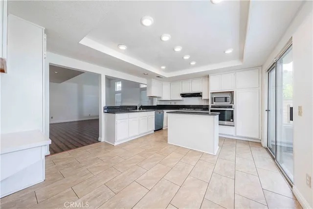 a kitchen with stainless steel appliances kitchen island granite countertop a refrigerator and a stove top oven