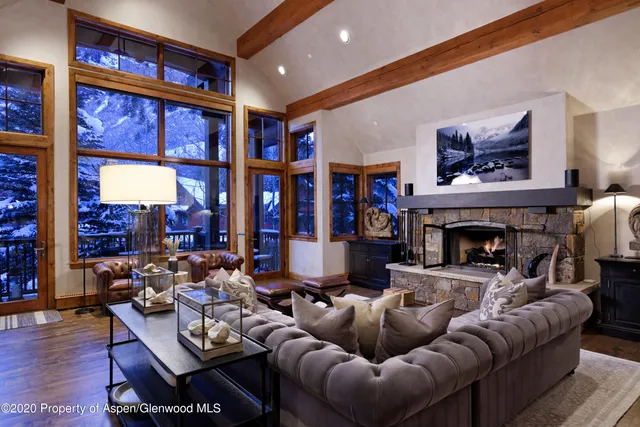 a living room with furniture a fireplace and floor to ceiling windows