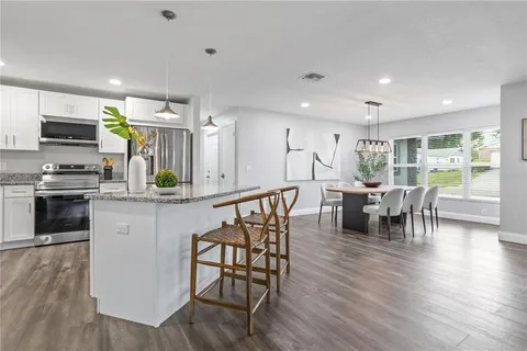 a kitchen with stainless steel appliances wooden floor dining table and chairs
