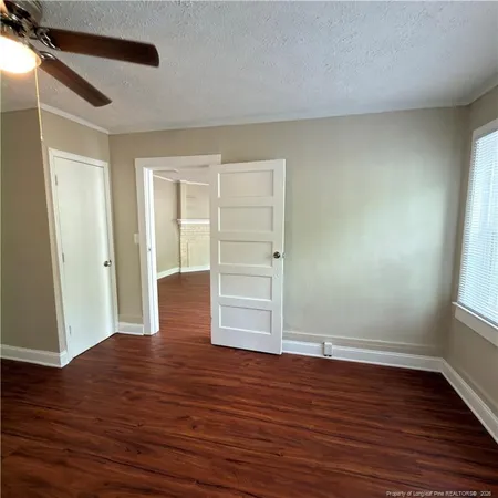 an empty room with wooden floor closet and windows
