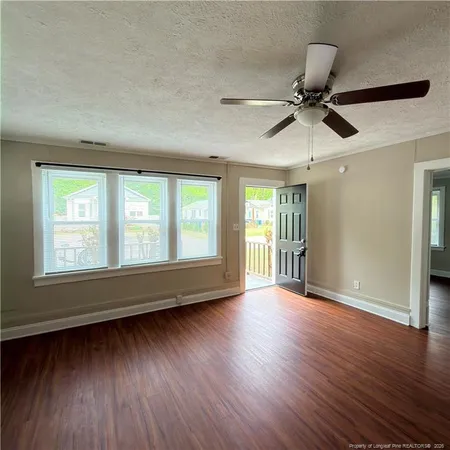 a view of an empty room with wooden floor and a window