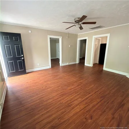 a view of an empty room with wooden floor and a ceiling fan