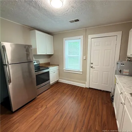 a kitchen with granite countertop a refrigerator and a stove top oven
