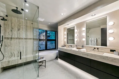 a bathroom with a double vanity sink a toilet a mirror and shower