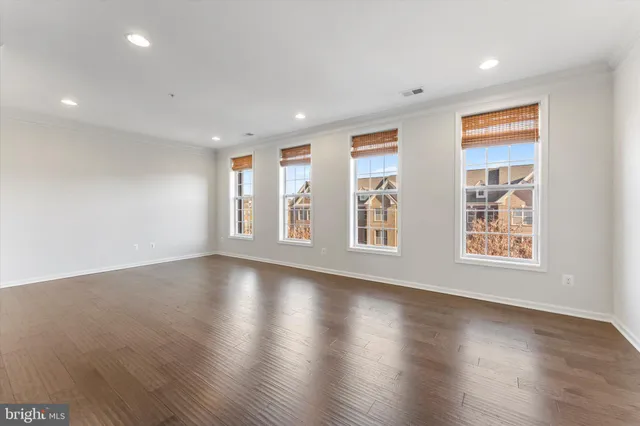 a view of an empty room with wooden floor and window