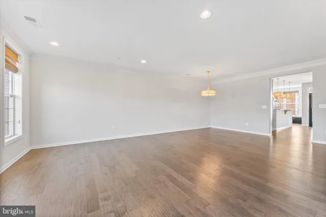 an empty room with wooden floor and windows with curtains