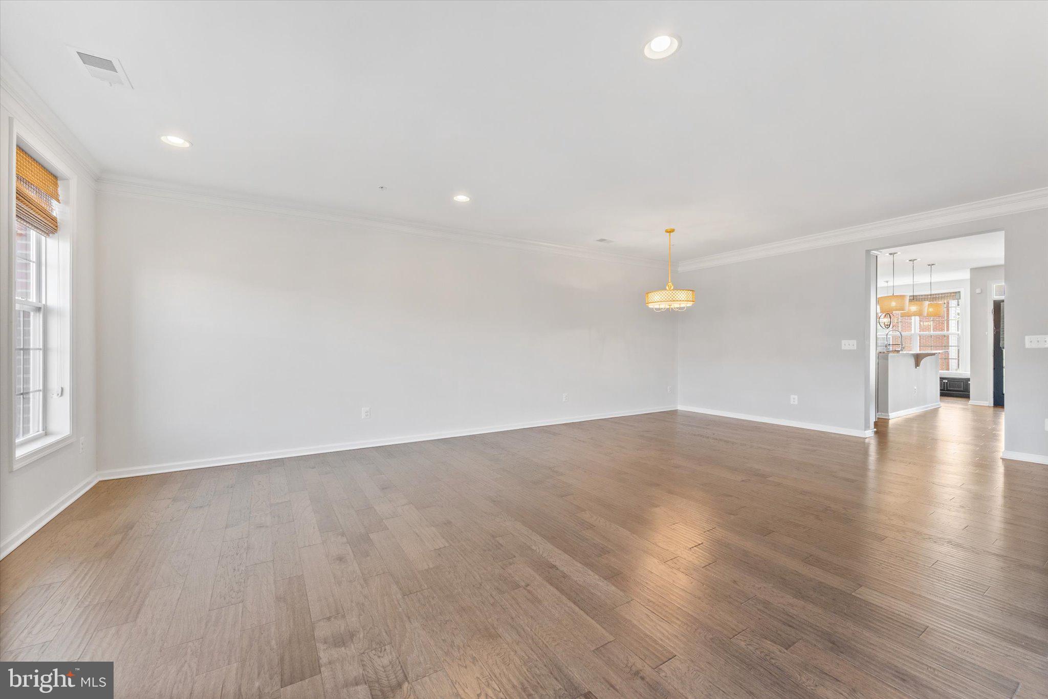 23483 Logans Ridge Terrace Ashburn, VA 20148 - Photo 18 of 35 an empty room with wooden floor and windows with curtains