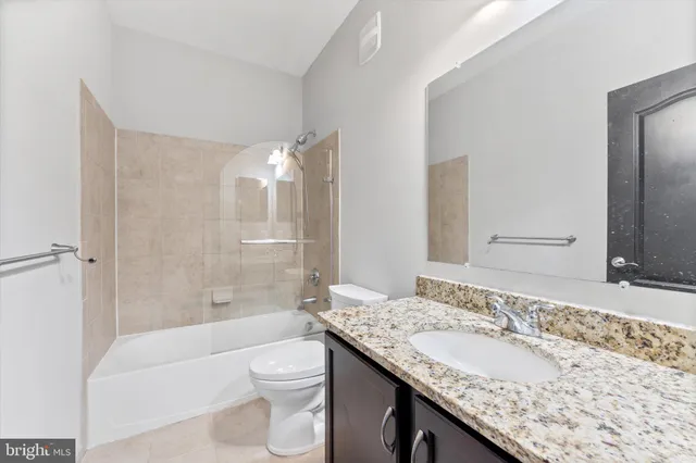 a bathroom with a granite countertop sink toilet mirror and bathtub