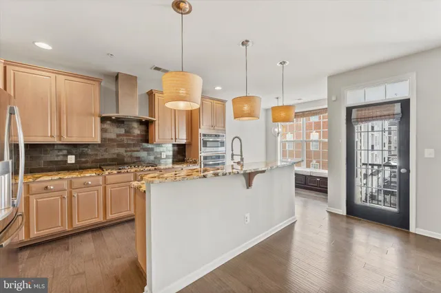 a kitchen with stainless steel appliances kitchen island granite countertop a stove a sink and white cabinets
