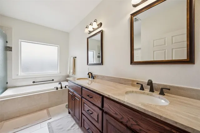 a bathroom with a tub a window and a glass door shower