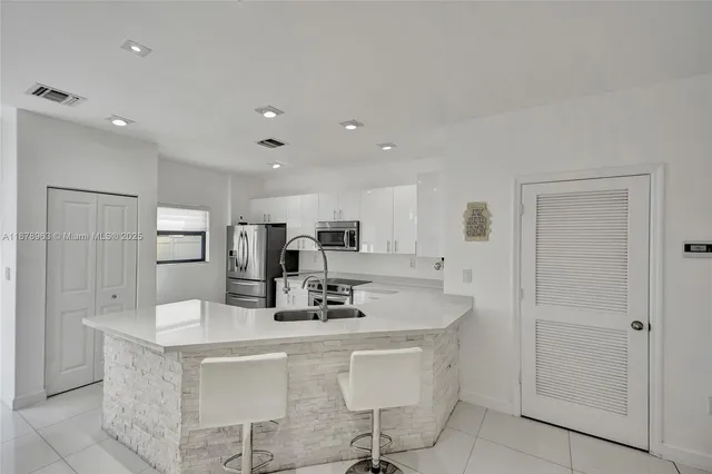 a kitchen with stainless steel appliances kitchen island sink refrigerator and cabinets