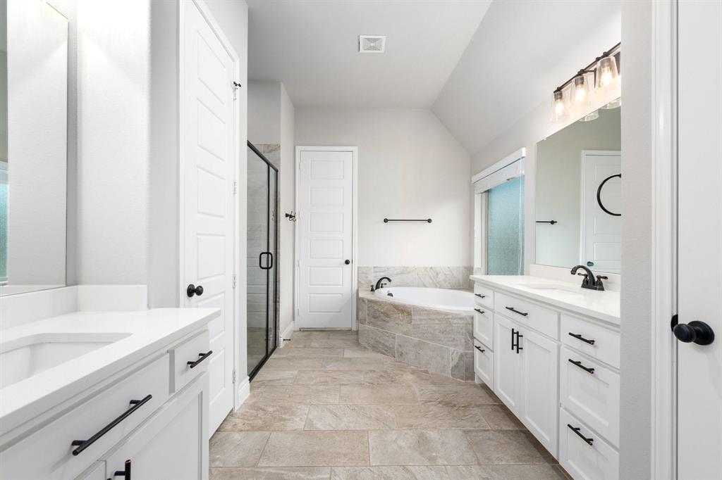 1501 Calcot Lane Forney, TX 75126 - Photo 17 of 34 Bathroom featuring dual white vanities with black hardware, a corner soaking tub, a framed glass shower, and tile flooring