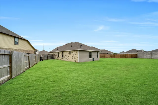 a view of a big house with a big yard plants and large trees