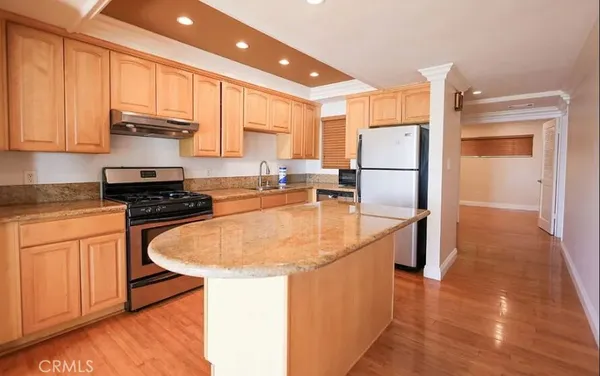 a kitchen with kitchen island a sink a stove a refrigerator and cabinets