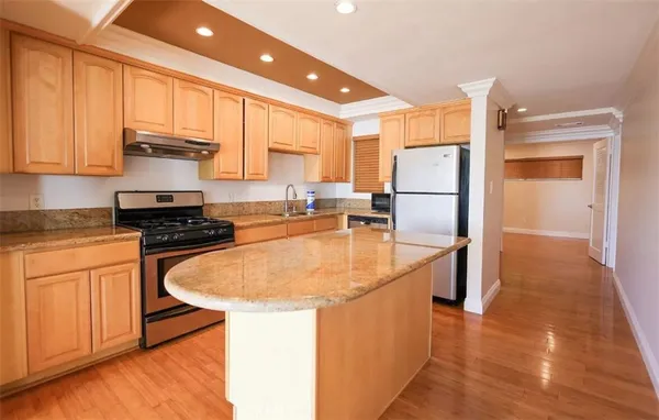 a kitchen with kitchen island a sink a stove a refrigerator and cabinets