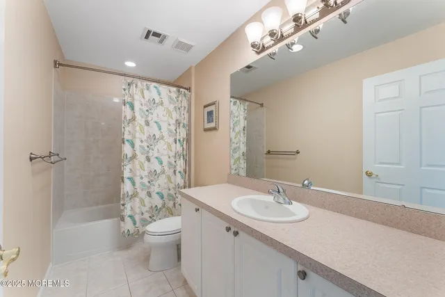 a bathroom with a granite countertop sink a toilet a mirror a bathtub and shower