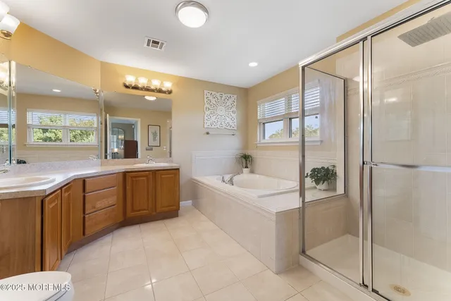 a large bathroom with a double vanity sink a large mirror and a bathtub