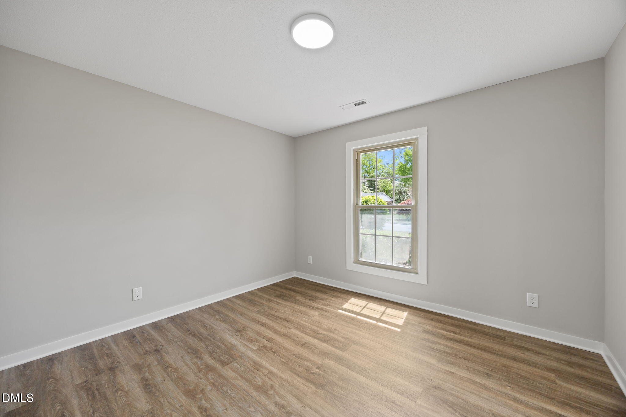 309 Rippling Stream Road Durham, NC 27704 - Photo 12 of 45 an empty room with wooden floor and windows