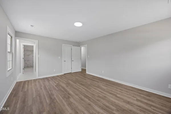 a view of an empty room with wooden floor and a window