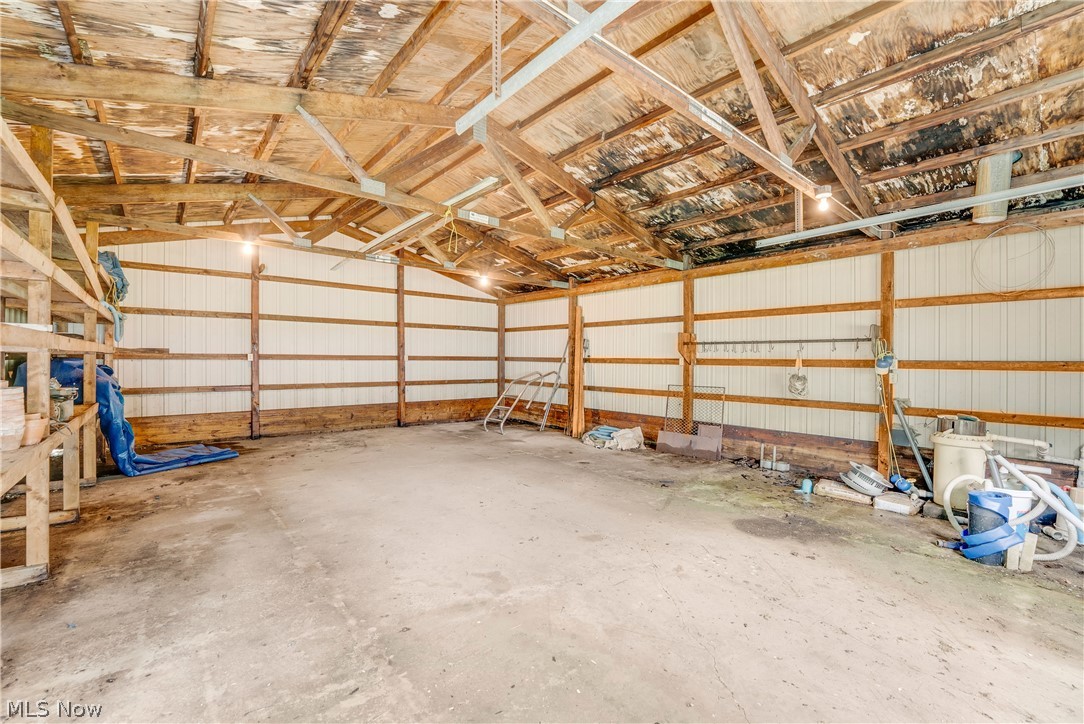 16107 Moseley Road Madison, OH 44057 - Photo 26 of 40 Spacious barn interior featuring exposed wood beam construction, corrugated metal siding, concrete flooring, and overhead lighting