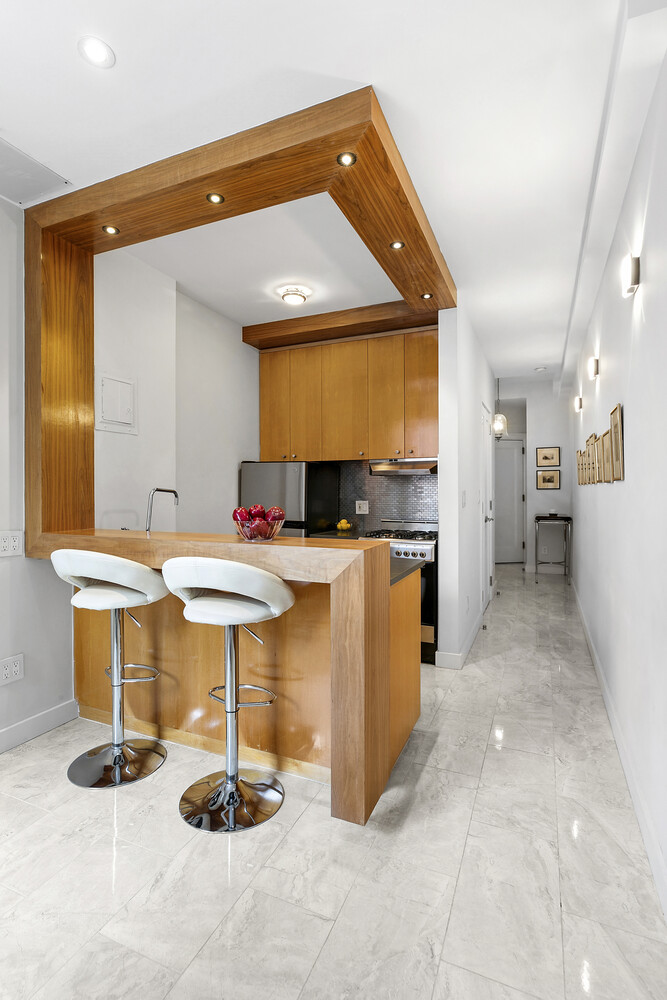 156 East 79th Street, Unit 9F Manhattan, NY 10075 - Photo 6 of 12 a kitchen with stainless steel appliances kitchen island granite countertop a sink and a refrigerator