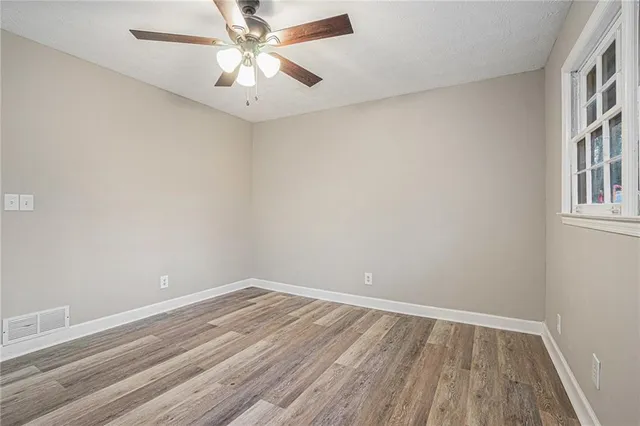 an empty room with a window and a fan