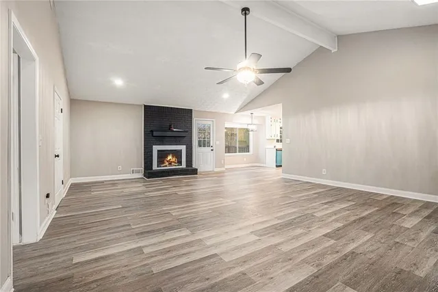 an empty room with wooden floor windows and ceiling fan