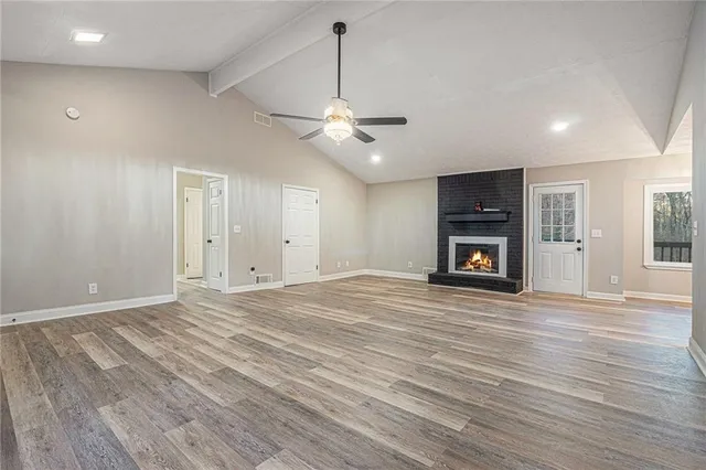 a view of empty room with fireplace and wooden floor