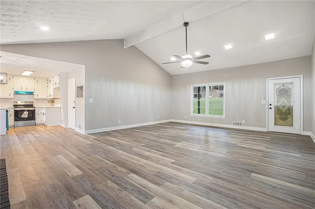an empty room with wooden floor a ceiling fan and windows
