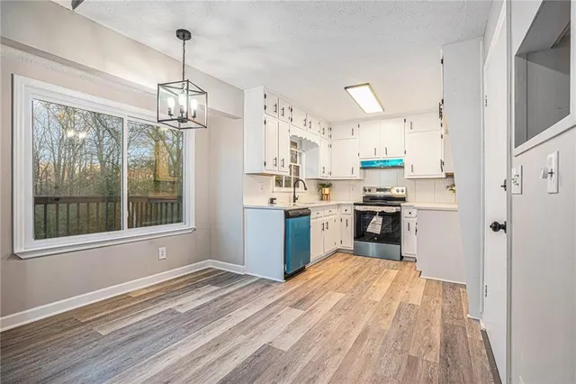 a large kitchen with stainless steel appliances granite countertop a refrigerator a sink dishwasher a stove and white countertops with wooden floor