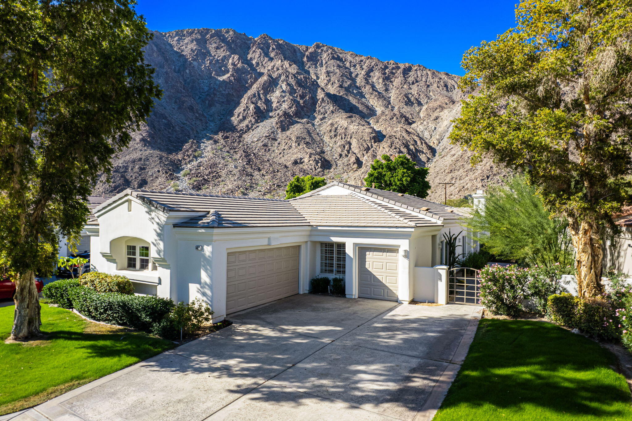 54275 Riviera La Quinta, CA 92253 - Photo 2 of 50 a front view of a house with a garden and trees