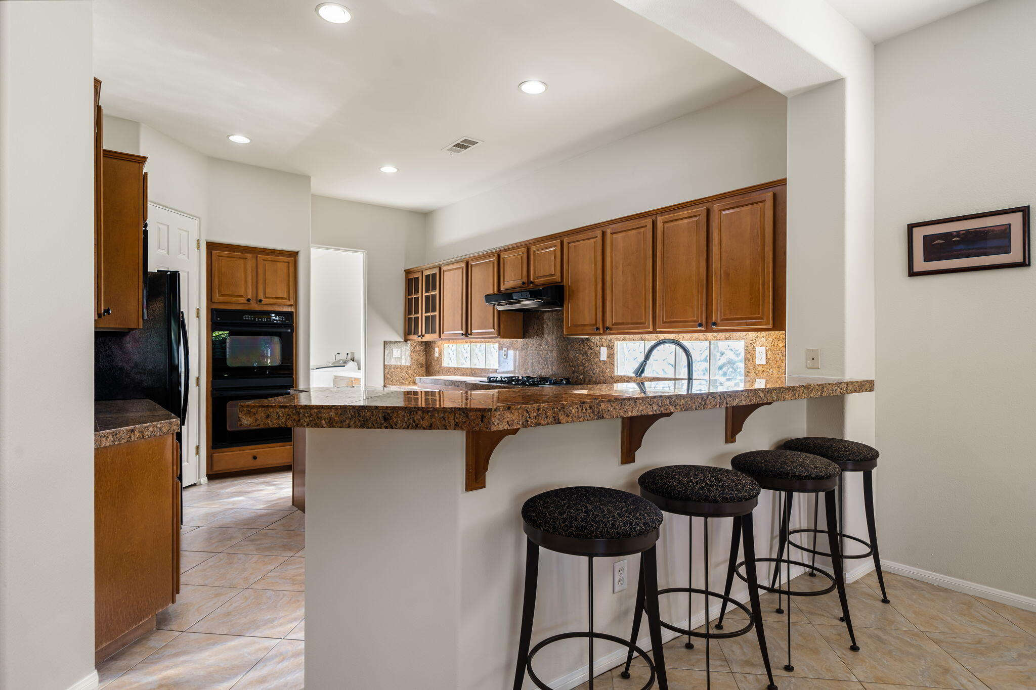 54275 Riviera La Quinta, CA 92253 - Photo 22 of 50 a kitchen with granite countertop a table chairs stove refrigerator and cabinets