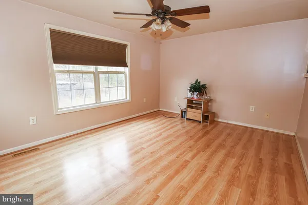 an empty room with wooden floor fan and windows